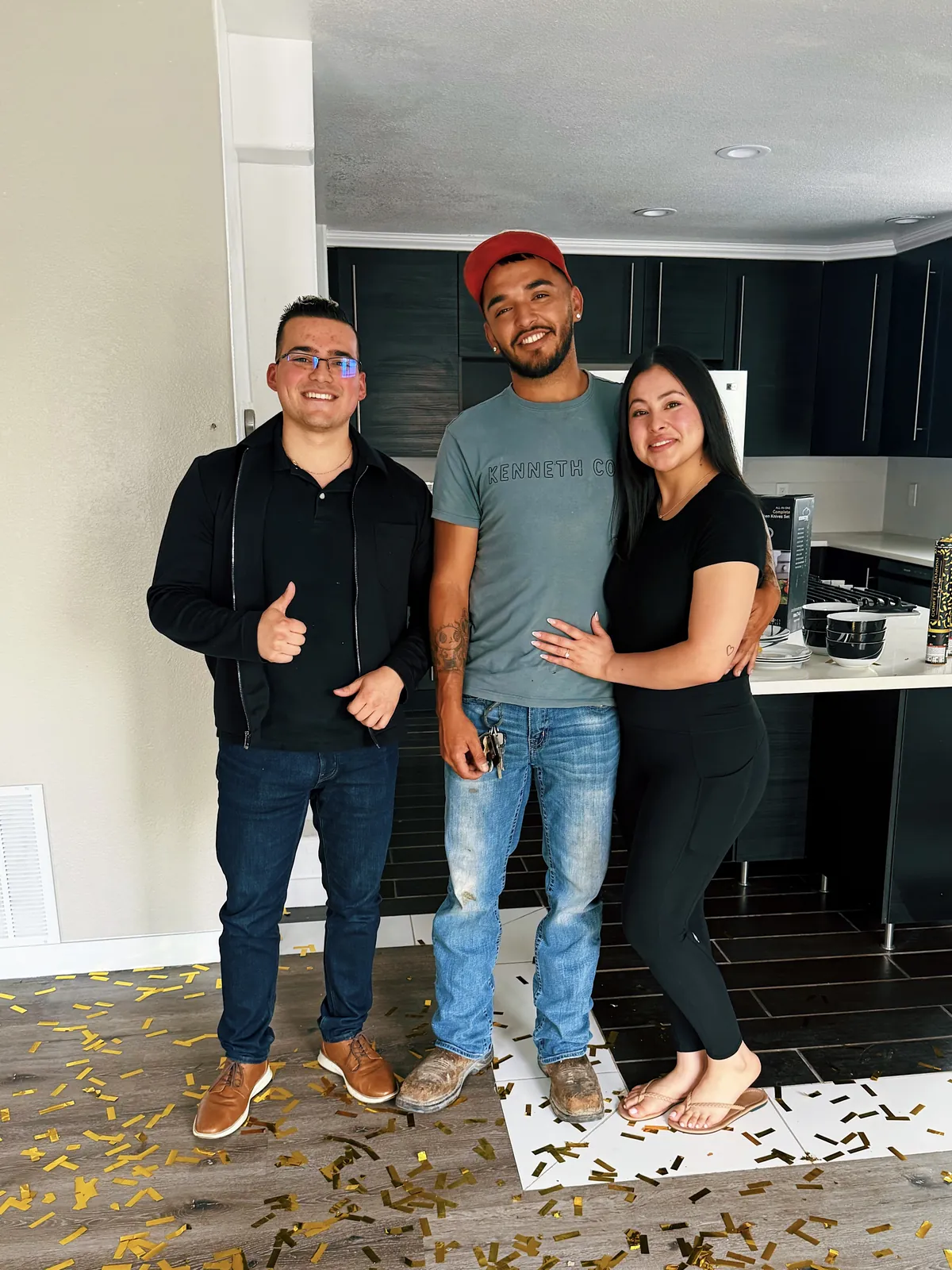 Joseph Loya giving a thumbs up in a new kitchen with Carolina and Jose, who hold the keys to their new home